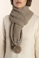 Bufanda tejida a mano en punto arroz color beige, con pompones en los extremos.
