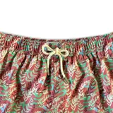 Short de baño blanco con estampado de hojas de palmera en tonos verde, rojo y amarillo.