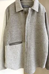 Camisa de hombre estilo leñadora con diseño patchwork en tonos beige y marrón. Presenta coderas, cartera americana y bolsillo ojal en el delantero. Confeccionada en lana fina sin teñir.