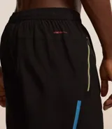 Bermuda deportiva negra sin estampado, con cintura elástica ajustable con cordón, y bolsillo lateral con cierre de cremallera contrastante.