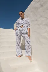 Pantalón de lino blanco con estampado floral azul, de tiro medio y corte semi-oxford con tajos en el ruedo.