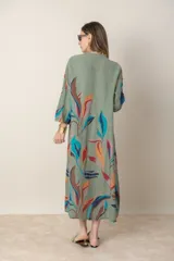 Vestido largo de lino color verde militar con estampado de hojas en tonos azul, naranja y marrón. Tiene cuello mao con botones, mangas tres cuartos y un bolsillo en el pecho.