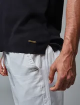 Remera tejida tipo polo color negro, de corte regular fit, con cuello y puños con ribete en contraste de color blanco, cartera con tres botones y logo bordado en la pechera.