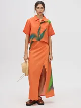 Falda pareo larga color naranja con estampado de hojas en verde y azul.