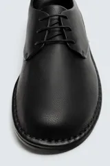 Zapato de cordones tipo derby, color negro, con capellada de cuero abatanado, plantilla de cuero y suela ultrafina.