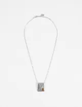 Collar plateado con cadena fina y dije geométrico rectangular con textura martillada y una piedra ovalada color ámbar incrustada.