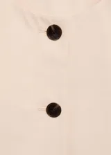 Top color crema, de corte crop, cuello redondo y sin mangas. Cierre frontal con botones y forro interior.