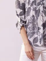 Blusa de gasa estampada con cuello a la base, escote en V y botones. Delantera con detalle plisado y largo de manga regulable con presilla y botón.