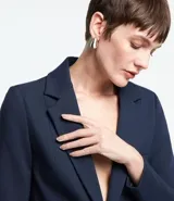 Blazer femenino de corte alargado, color gris oscuro, con cuello solapa, cierre frontal de dos botones y bolsillos incorporados.