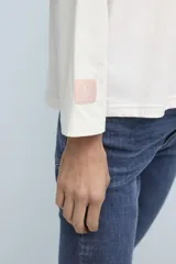 Remera blanca de manga larga con cuello redondo y pequeño logo estampado en el pecho y en la manga.