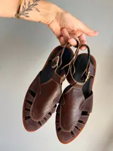Sandalias de cuero marrón con diseño de tiras y hebilla lateral.