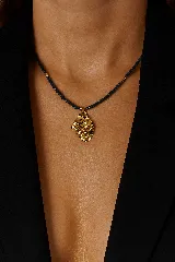 Collar corto con cuentas facetadas de color azul oscuro y dije irregular martillado de acero dorado.