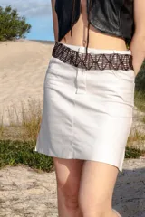 Minifalda de cuero ovino color blanco, con diseño que imita un jean, incluyendo costuras visibles y bolsillos delanteros y traseros.