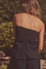 Top negro strapless de tejido fluido con frunces ajustables con cordones en los laterales y aberturas laterales en el ruedo.