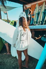 Buzo color crudo con cuello redondo y puños y cintura acanalados. Estampado en la espalda con diseño de palmera y texto enmarcado en damero.