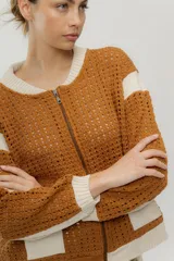 Chaqueta estilo bomber tejida color marrón con detalles en beige, cierre frontal y bolsillos delanteros.