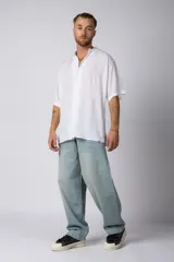 Camisa blanca de manga corta con cuello camisero y botones frontales. Presenta un corte oversize y confección en tela ligera.