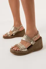 Sandalias de cuero color dorado con plataforma y taco de cuña forrado en gamuza marrón.