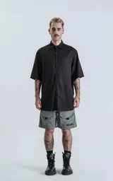 Camisa negra de manga corta con cuello clásico y cierre frontal con botones.