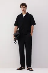 Pantalón negro de lino con corte recto, cintura elastizada con cordón ajustable, bolsillos laterales y bolsillo trasero.