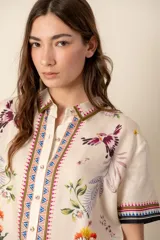 Camisa de seda color blanco con estampado de flores y aves, de corte recto, manga corta y botones forrados.