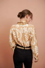 Camisa beige con estampado de hojas blancas, de corte clásico y manga larga.