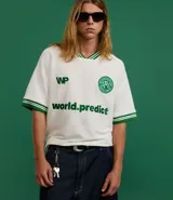 Remera deportiva oversized de mangas cortas, color blanco con detalles en verde en cuello y mangas. Presenta logo y texto estampados en el frente.