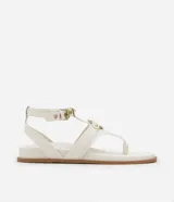 Sandalia plana de cuero sintético color blanco, con tiras superpuestas, detalle de aro metálico y cierre ajustable con hebilla.