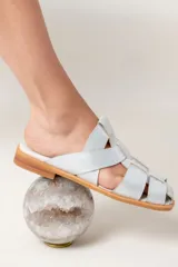 Zuecos de cuero vacuno color celeste con diseño de tiras entrecruzadas y suela de madera.