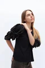 Remera color beige con mangas cortas y volados con borde naranja.