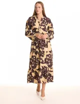 Vestido maxi de crepe estampado con flores grandes en tonos beige y marrón oscuro. Presenta escote en V con botones, mangas largas anchas con botón en los puños, y cintura con pasadores y cordón de ajuste.