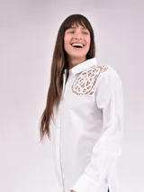 Camisa blanca de manga larga con detalles de encaje en los hombros.
