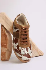 Zapatillas deportivas bajas con estampado animal print de vaca en blanco y marrón.