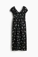 Vestido largo negro con estampado floral blanco, de tejido liviano de mezcla de lino y viscosa. Modelo con mangas cortas abullonadas, escote corazón con tiras finas y copas preformadas con frunces. Elástico fino en escote, hombros, mangas y cintura. Cierre lateral oculta y bajo recto con tajo pronunciado en un lado.
