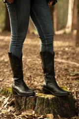 Bota texana de cuero vacuno negro con detalles bordados en dorado y plateado en la caña. Tiene taco de madera con folia de cuero de 5cm, entre suela de goma de 1cm, inclinación de horma de 4cm, altura de caña de 31cm y cierre YKK del lado interno. La horma es de punta fina, ancha y cómoda.