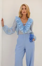 Blusa celeste con cuello en V y volados, mangas largas abullonadas y lazos en el escote.