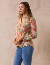 Blusa de gasa estampada a rayas verticales en tonos celeste, lila, naranja y marrón. Tiene cuello a la base con escote en V y botones. Delantera con bolsillo aplicado. Largo de manga regulable con presilla y botón. Terminación anudada opcional.