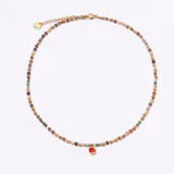 Gargantilla tipo choker compuesta por pequeñas cuentas facetadas en tonos tierra, verdes y negros, con un dije central de cristal cuadrado color rojo anaranjado engarzado en metal dorado.