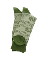 Calcetines largos color beige con diseño de montañas y árboles en verde. El puño, talón y puntera son de color verde oscuro.