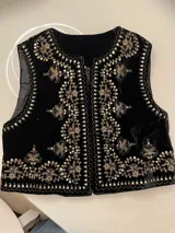 Chaleco negro de terciopelo con bordados dorados de flores y lentejuelas.