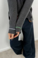Sweater de punto gris con cuello en V y ribetes en contraste.