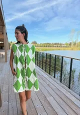 Vestido camisero corto con estampado de rombos en tonos beige, marrón y blanco. Tiene cuello camisero, cierre frontal con botones y corte holgado.