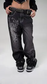 Pantalón jean negro con estampado de arabescos en color gris, de tiro bajo y corte baggy.