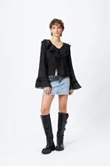 Blusa blanca de gasa con escote en V y volados en el cuello y las mangas largas. Se ata con lazos finos al frente.