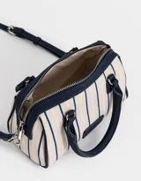 Cartera bowling con estampado de rayas verticales color beige y azul marino. Tiene doble asa corta de mano y correa regulable y desmontable. Incluye cierre superior y tag frontal de cuerina con el logo 'The Brunch Club'.