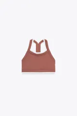 Top deportivo color ladrillo con escote redondo y tirantes blancos.