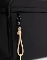 Bolso bandolera negro de tela deportiva con correa regulable y desmontable estampada, cierre superior, bolsillo frontal con cierre y bolsillos laterales con tira de ajuste.