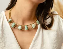 Gargantilla con piedras en tono verde claro, montada en un diseño de metal dorado.