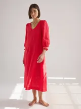 Vestido midi de lino color lila con escote en V y mangas 3/4 abullonadas con puño elástico. Presenta paneles laterales en denim y costuras a la vista en color rojo.