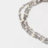 Pulsera plateada de tres hilos con cuentas blancas y cierre de gancho.